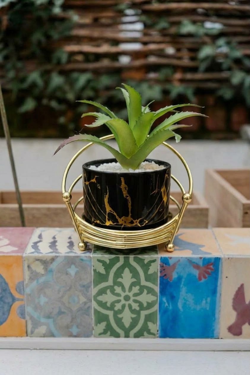 Glossy black ceramic pot with gold marble veins in a metallic wire cradle holder